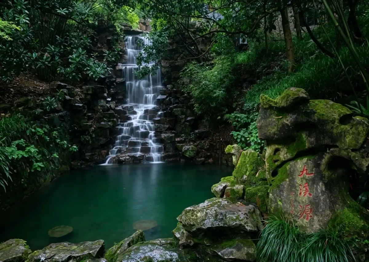 Water flows down tiered rocks into a greenish-blue pool, and red inscriptions are visible on the moss-covered rock walls.