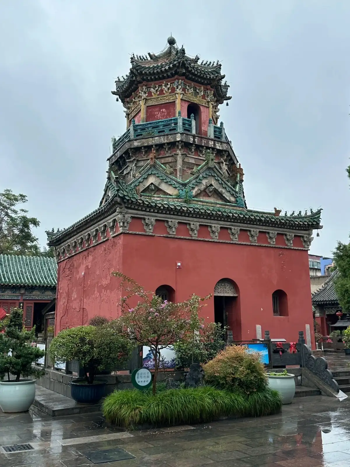 A multi-story pavilion on a red plinth after the rain
