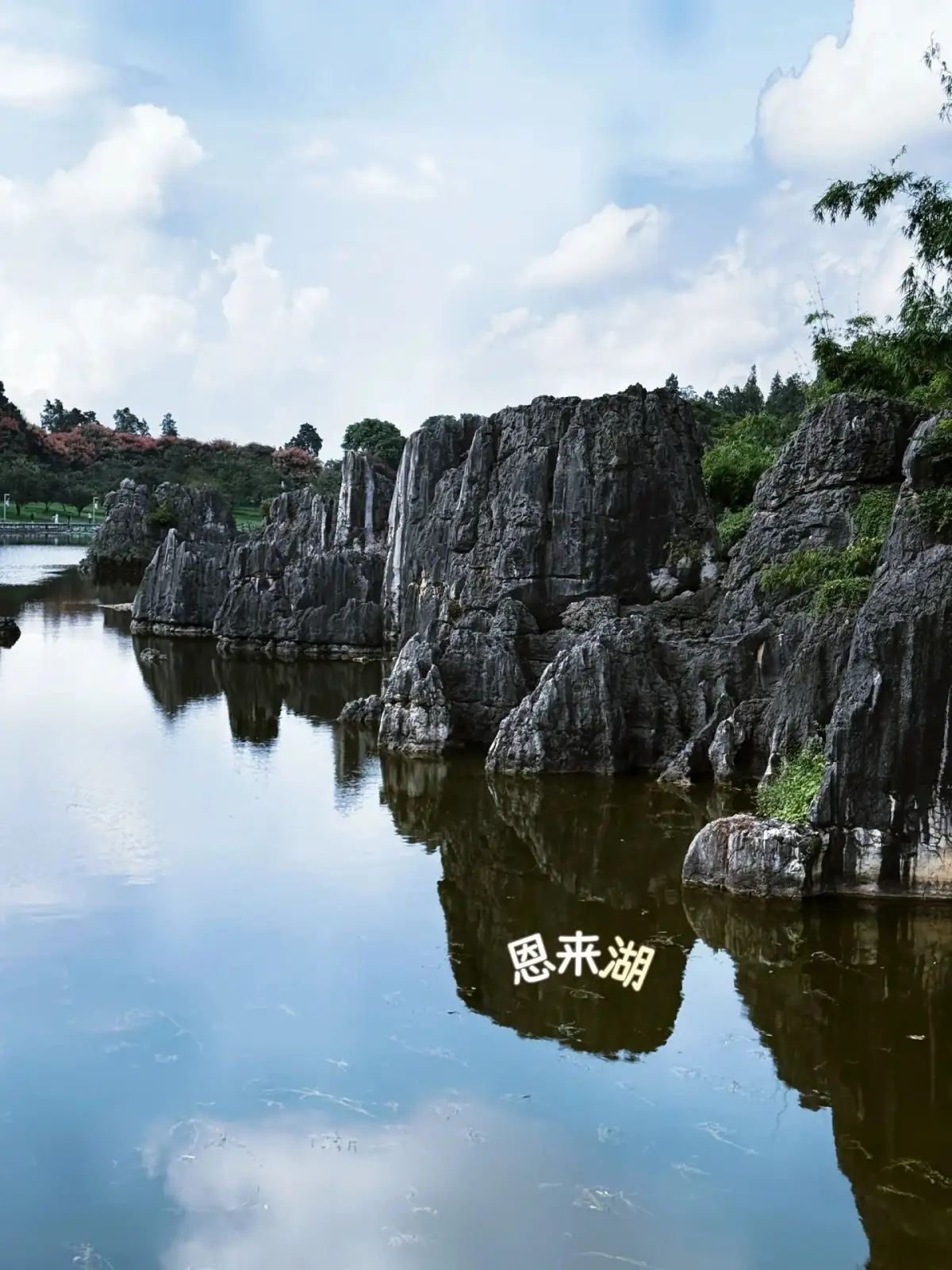 lake surface reflects rows of limestone cliffs and white clouds; the image includes a description of the scenic spot.