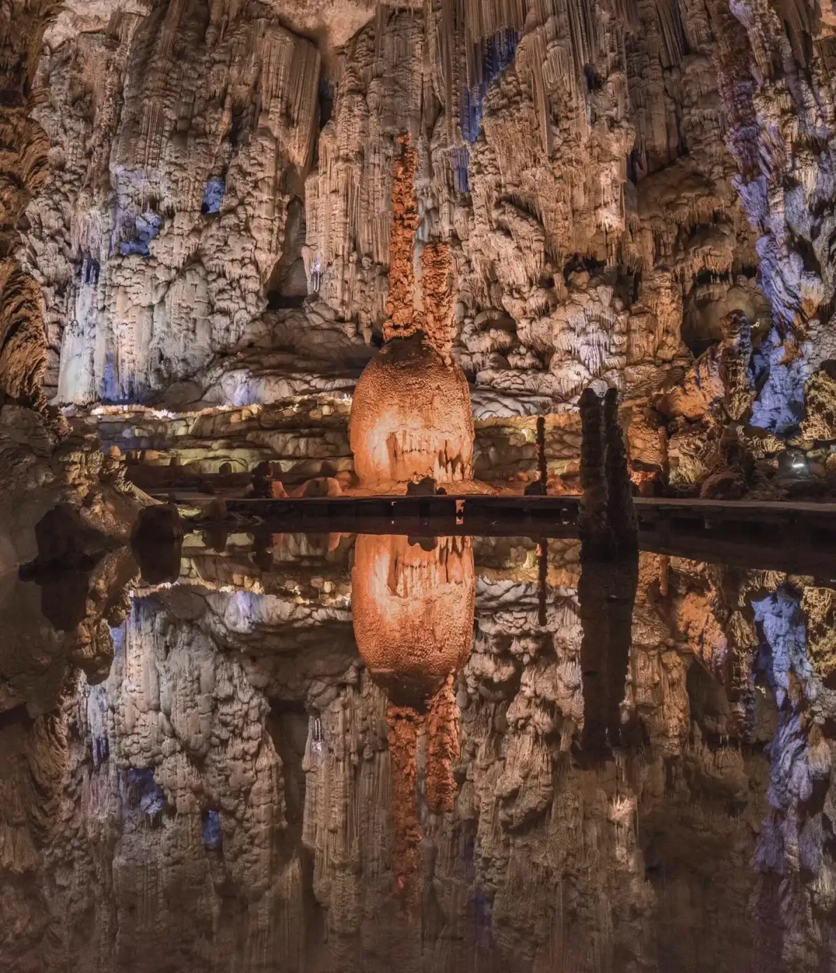The water surface inside the cave reflects the stone pillars and the walking paths along the shore