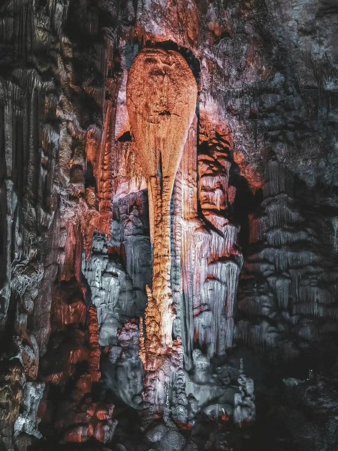 Curtain-like cave deposits hanging beneath orange lighting