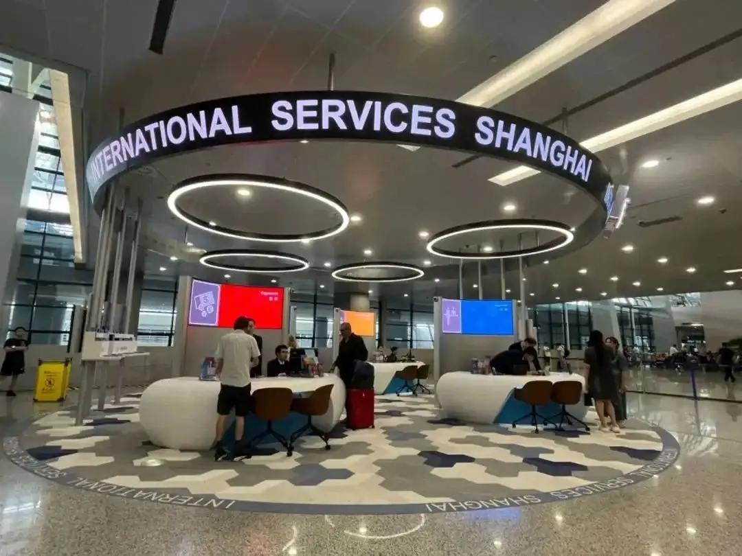 写有International Services Shanghai的机场服务岛与工作人员、旅客背影