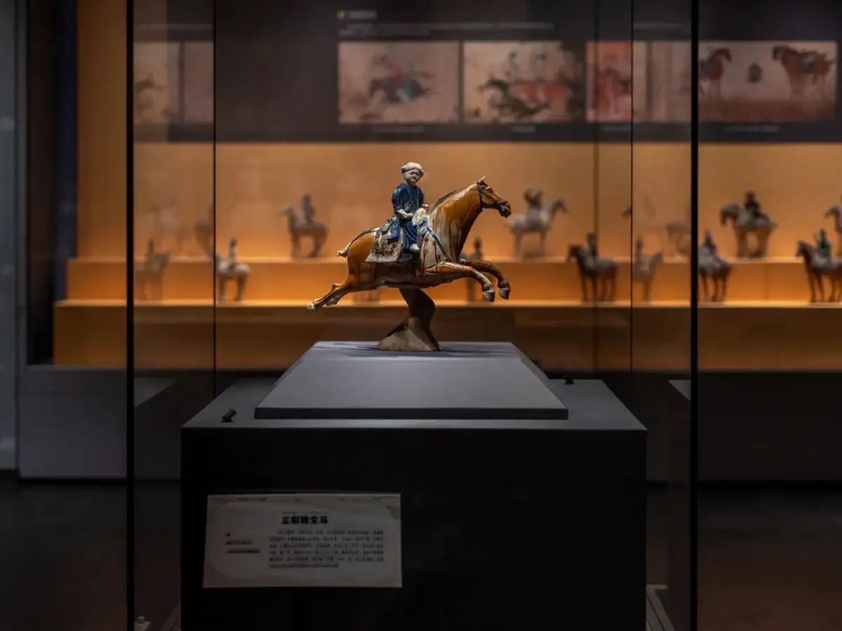 The ceramic equestrian sculpture in the glass display case and the explanatory plaque below it