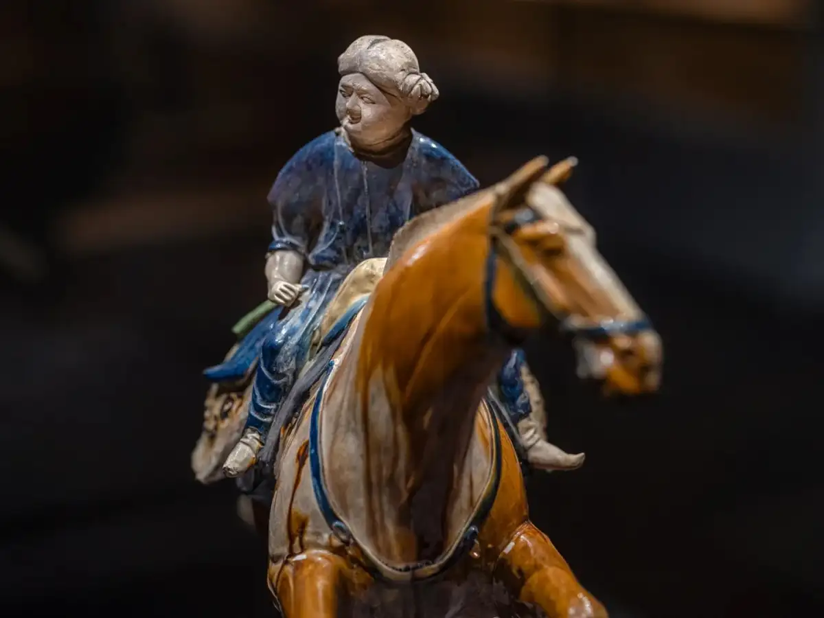 Close-up of the blue-clad ceramic rider’s head, drapery, and the horse’s head