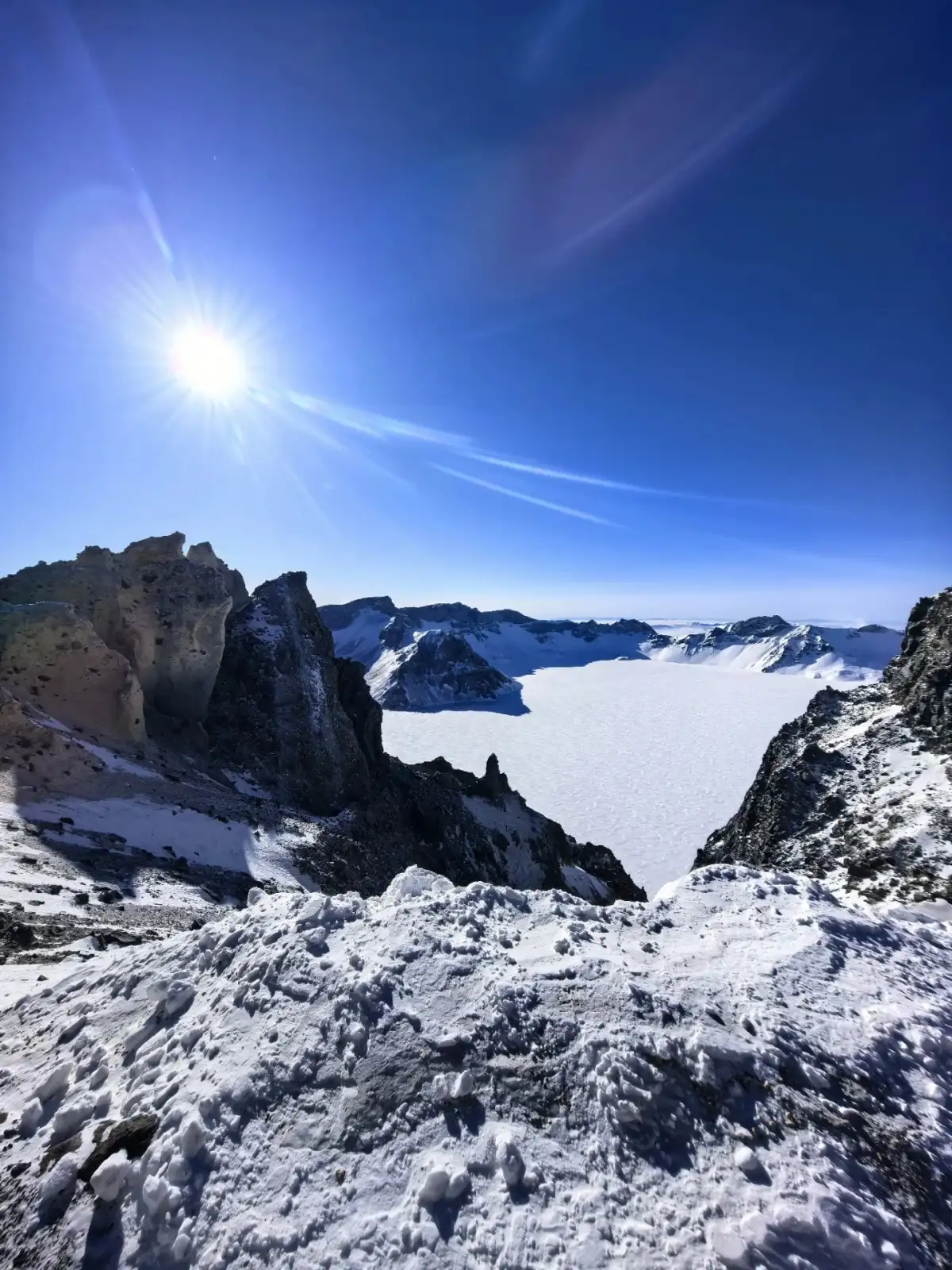 阳光下的长白山雪面与岩石