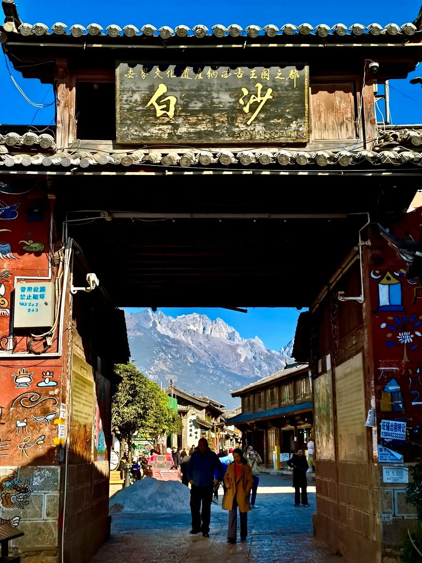 The archway at Baisha Ancient Town in Lijiang and the snow-capped mountains in the distance