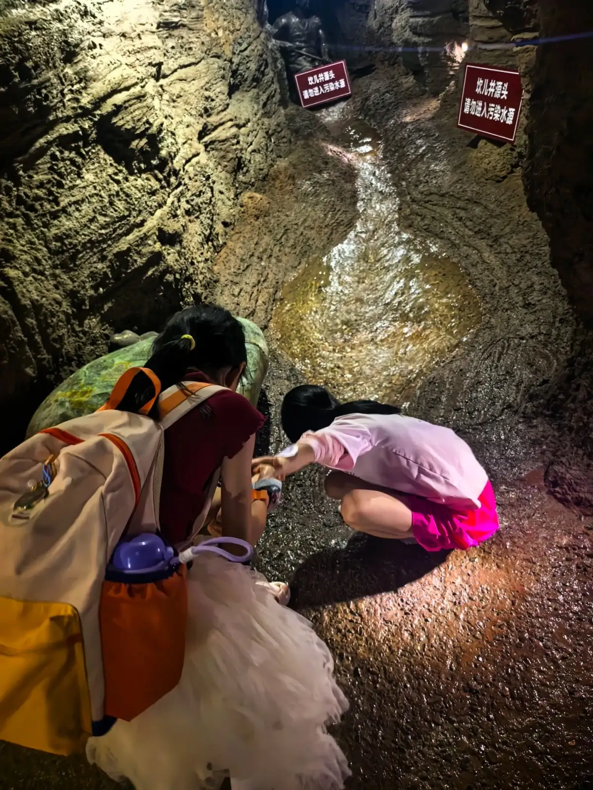 交河驿坎儿井地下水渠与俯身参观者